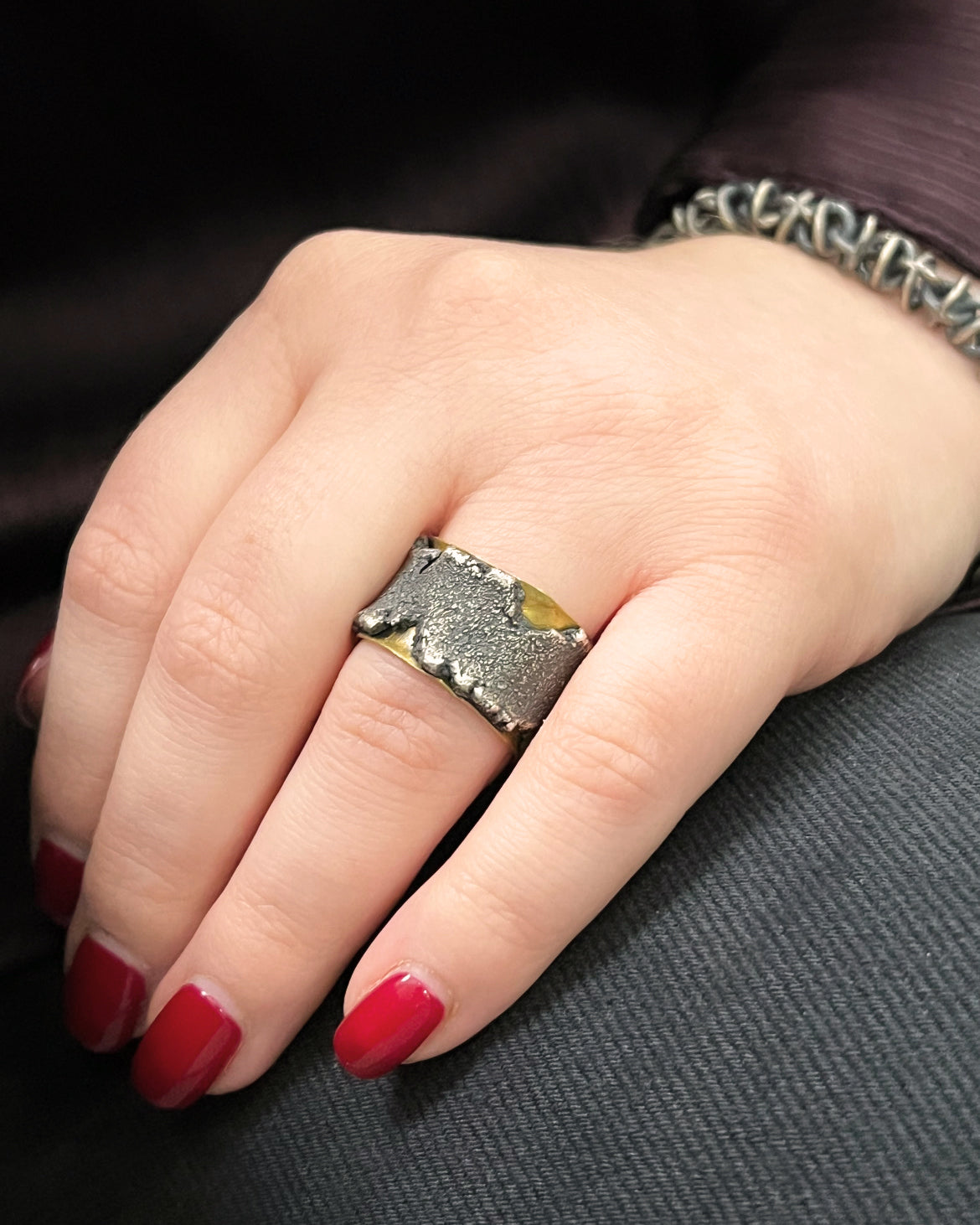 lady's hand wearing a wide texture silver and gold band