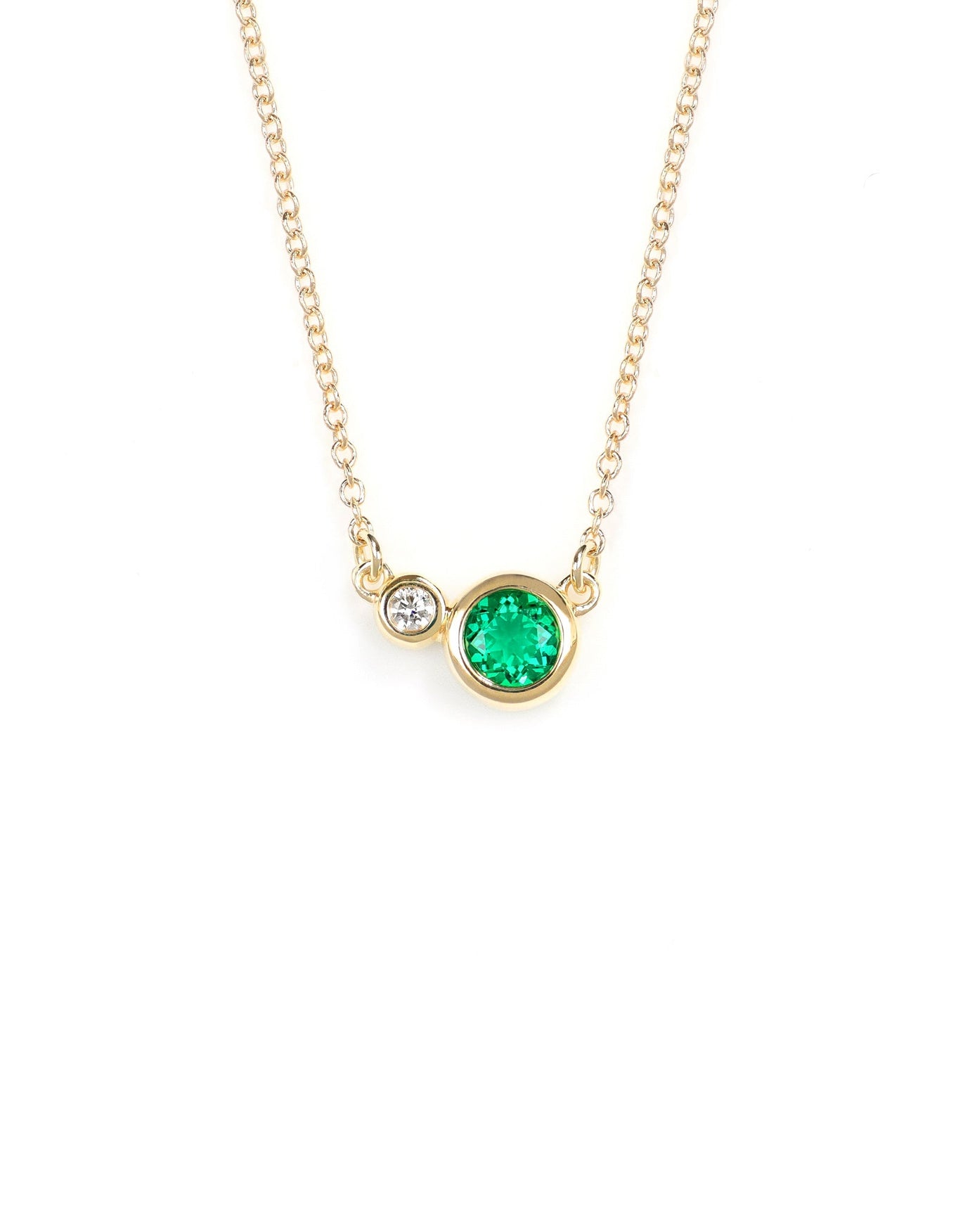 round emerald and diamond bezel set in yellow gold necklace on white background