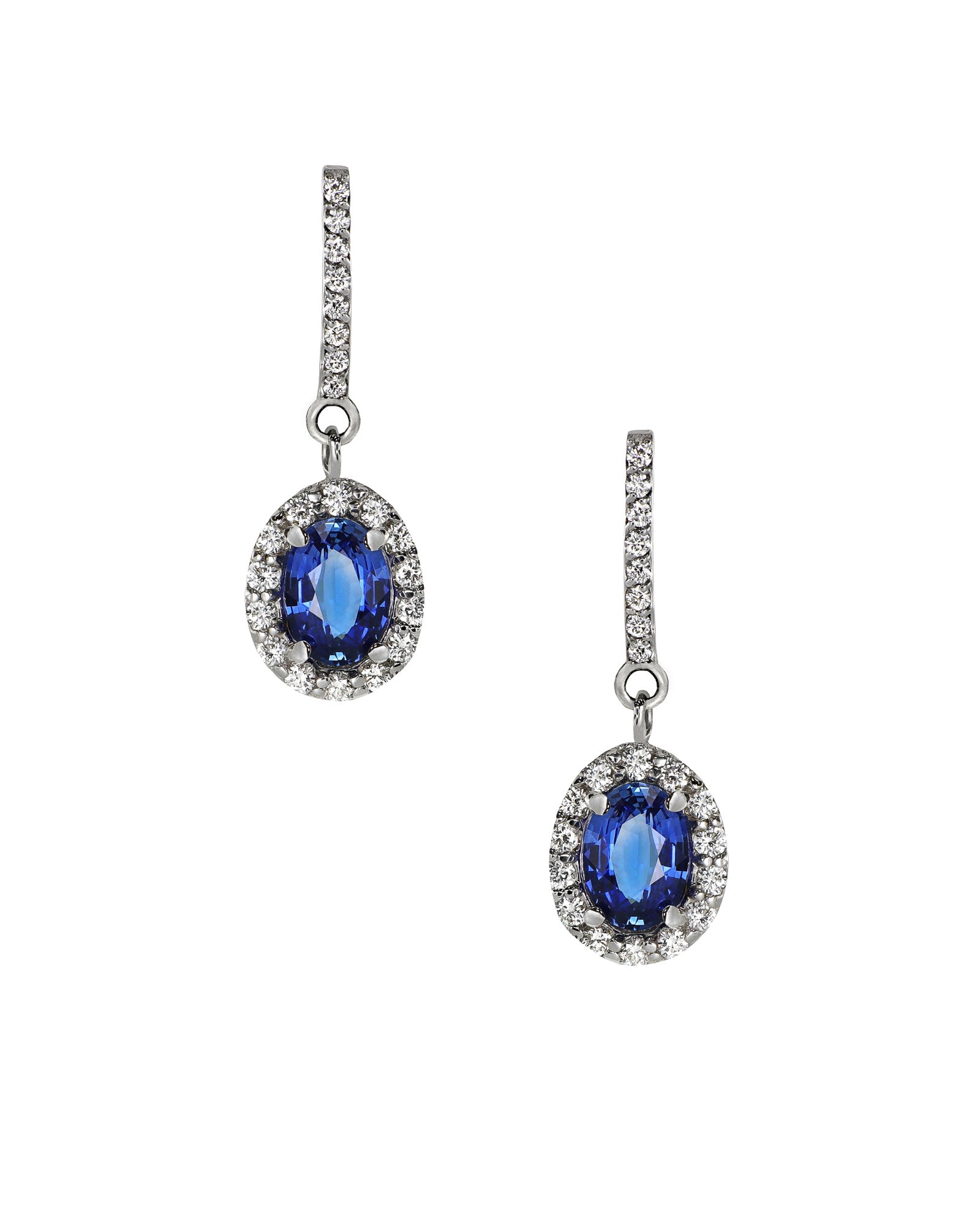 oval vivid sapphire  halo earrings dangling from diamond bar earrings. On white background