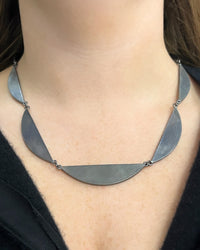 Silver necklace worn by a person with a blurred background